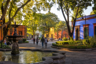 Plaza arbolada de Coyoacán con fuente y arquitectura histórica al amanecer