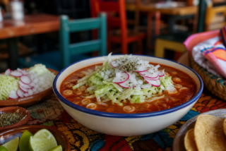 Pozole rojo mexicano servido con lechuga, rábanos, cebolla y tostadas