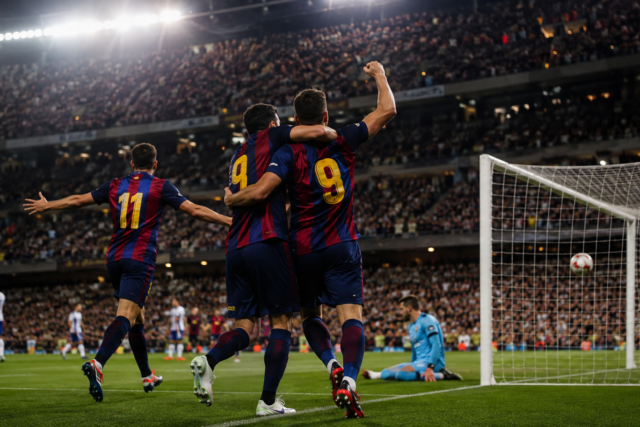 Jugadores de un equipo azul y granate celebran un gol en un estadio lleno.