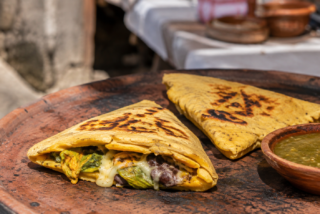 Itacates tradicionales recién cocidos sobre un comal de barro, acompañados de salsa verde