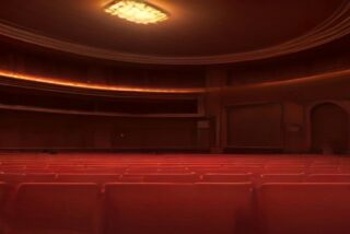 Sala de teatro clásica vacía con filas de butacas rojas, palcos curvos y luz cálida en el techo, alusiva a los boletos del FICM 2026