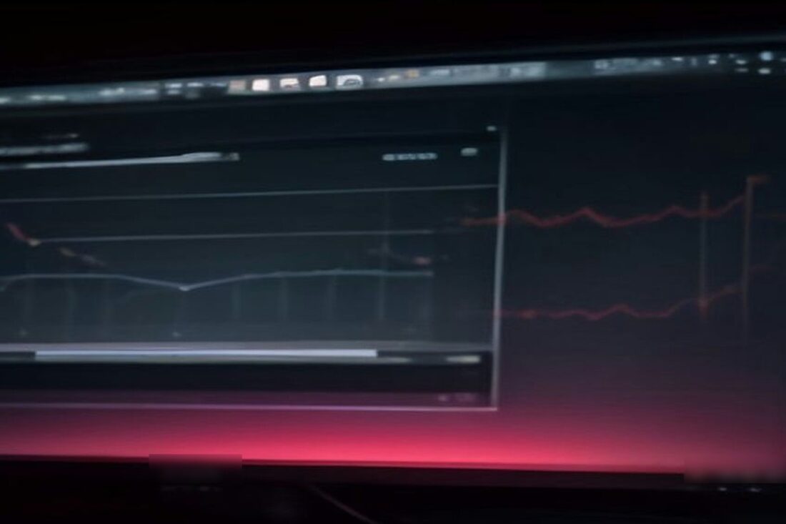 Monitor de computadora en una habitación oscura con líneas rojas de una gráfica financiera que brillan sobre la pantalla
