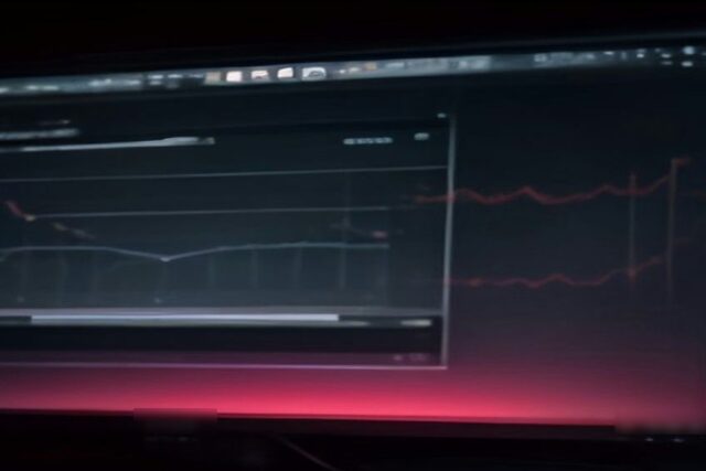 Monitor de computadora en una habitación oscura con líneas rojas de una gráfica financiera que brillan sobre la pantalla