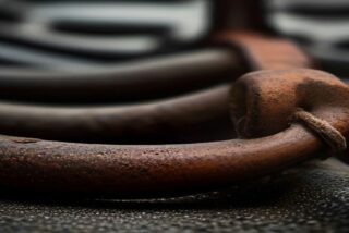 Primer plano de una cadena de hierro oxidada sobre una superficie metálica