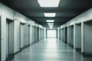Pasillo vacío de hospital con luz fluorescente y puertas a los lados, ilustración de la jornada de votación sindical, sin personas