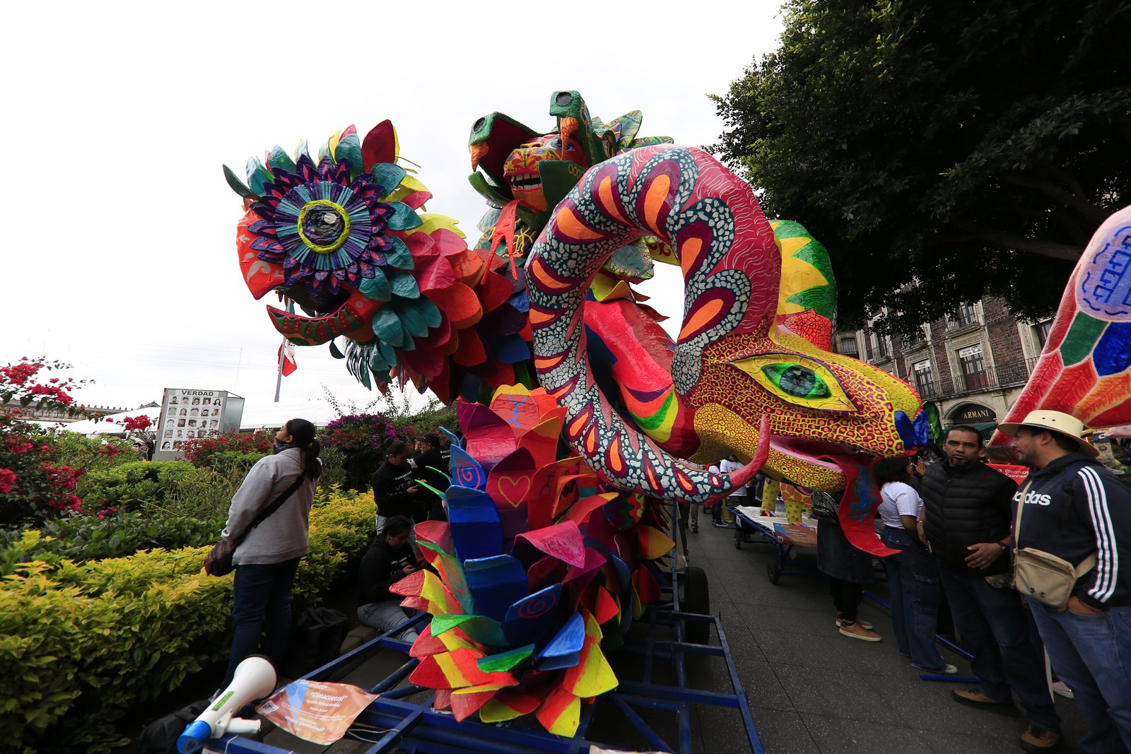 Alebrije monumental con forma de serpiente y flores multicolores junto a un jardín durante el desfile en la CDMX