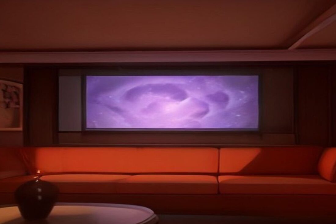 Sala en penumbra con un sillón naranja frente a una pantalla que proyecta un resplandor cósmico morado, alusiva al estreno de Dragon Ball Super: Beerus en streaming