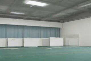 Salón comunitario vacío con mamparas blancas de votación alineadas, alusivo a las elecciones intermedias 2026 en Estados Unidos