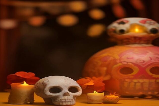 Calaveras decorativas de cerámica, velas encendidas y flores naranjas sobre una mesa, alusivas al Festival de Calaveras 2026 en Aguascalientes