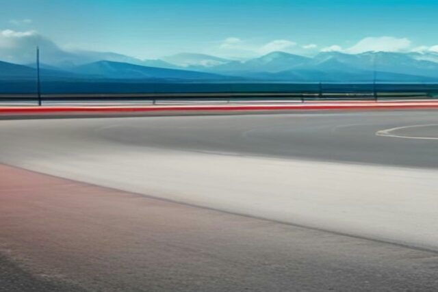 Pista de carreras vacía con una curva de asfalto, borde rojo y montañas al fondo bajo un cielo azul, alusiva al Gran Premio de México 2026