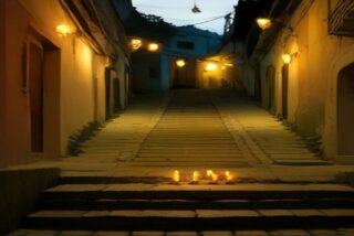 Callejón colonial iluminado de noche con velas encendidas sobre los escalones, alusivo al Hanal Pixán 2026 en Mérida