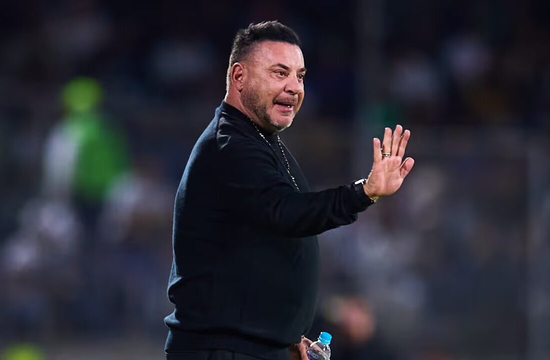 Antonio Mohamed, con suéter negro, levanta la mano en la cancha
