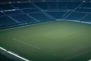 Estadio de futbol vacío de noche con gradas azules y la cancha de pasto verde iluminada por reflectores, alusivo a la Liguilla Apertura 2026 de la Liga MX