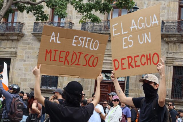 Manifestantes sostienen pancartas con las frases "Al estilo Mierdisco" y "El agua es un derecho" frente a Palacio de Gobierno de Jalisco durante la marcha Agua Limpia