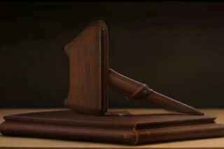 Mazo de madera apoyado sobre una base de madera encima de un escritorio, con fondo oscuro y luz cálida