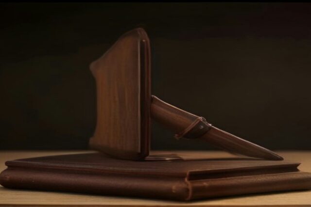 Mazo de madera apoyado sobre una base de madera encima de un escritorio, con fondo oscuro y luz cálida
