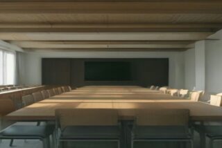 Sala de juntas institucional vacía con mesa de conferencia de madera larga y sillas bajo luz natural suave, sin personas ni logos.