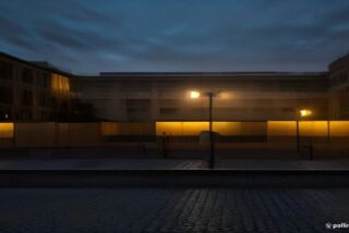 Patio institucional vacío con vallas policiales y patrullas estacionadas al atardecer en capital estatal mexicana, sin personas ni rostros