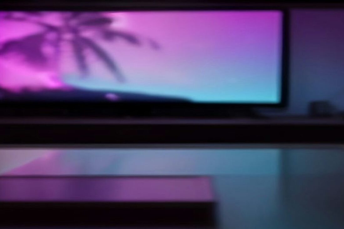 Televisor encendido con un atardecer de neón rosa y turquesa con siluetas de palmeras en una sala oscura, alusivo al precio de GTA 6 en México