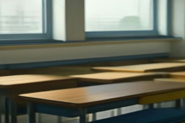 Salón de clases vacío con pupitres de madera alineados junto a ventanas con luz suave de la mañana, alusivo al registro de la Beca Rita Cetina