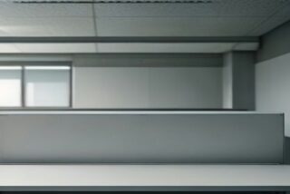 Escritorio de oficina vacío en espacio de reclutamiento con luz suave y cubículos al fondo, sin personas ni texto ni logos.