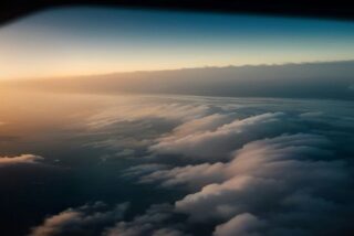 Vista desde la ventana de un avión de un mar de nubes sobre el océano al amanecer