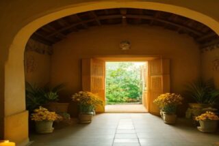 Pasillo con arco de una casa antigua, macetas con flores de cempasúchil a los lados y una puerta abierta hacia la vegetación, alusivo al Xantolo 2026 en la Huasteca potosina